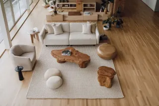 Un salon moderne et chaleureux avec des meubles en bois naturel et un tapis texturé clair.