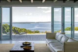 Un salon moderne et lumineux avec une vue panoramique sur l'océan depuis de grandes baies vitrées.