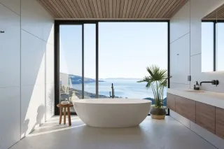 Une salle de bain moderne avec une baignoire blanche, offrant une vue panoramique sur la mer au travers de grandes baies vitrées.