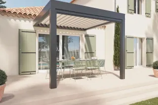 Une pergola moderne en métal ombrage une terrasse ensoleillée avec une table à manger élégamment dressée.