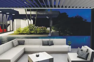 Une terrasse moderne et élégante avec un sofa blanc en angle, entourée de végétation luxuriante et surplombant une piscine à déb