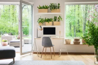 Un espace de bureau moderne et lumineux avec des plantes verdoyantes et une vue sur un jardin luxuriant.