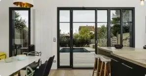 Une cuisine moderne avec des portes vitrées donnant sur un jardin avec terrasse et piscine.