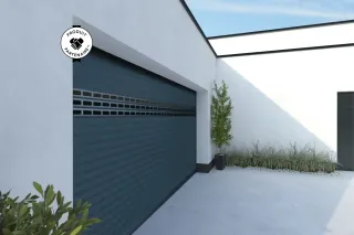 Portail de garage moderne gris anthracite dans une cour extérieure minimaliste avec des plantes vertes.