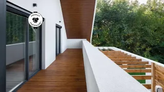 Balcon moderne avec parquet en bois et garde-corps blanc, offrant une vue sur une forêt verdoyante.