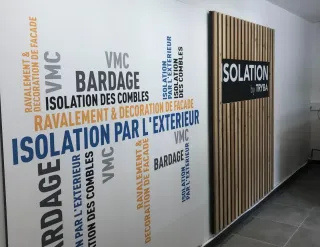 Une image montrant un mur avec des mots-clés sur l'isolation et le bardage entourant une partie en bois portant le logo 'Isolation