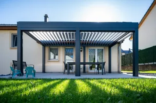 Pergola gris anthracite vue basse la lumière passe à travers les lamelles orientables