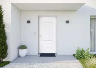 Une entrée de maison moderne avec une porte blanche, des murs clairs, et des plantes décoratives.