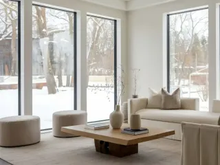 Un salon moderne et minimaliste avec de grandes fenêtres offrant une vue sur un paysage enneigé.