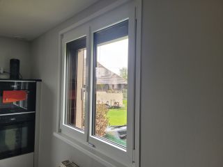 Fenêtre moderne en PVC blanche ouvrant sur un jardin depuis une cuisine équipée.