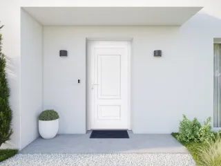 Une entrée de maison moderne avec une porte blanche, des murs clairs, et des plantes décoratives.