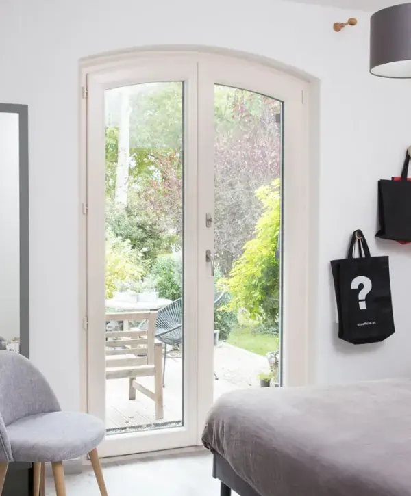 Une chambre lumineuse avec une grande porte-fenêtre donnant sur un jardin verdoyant.