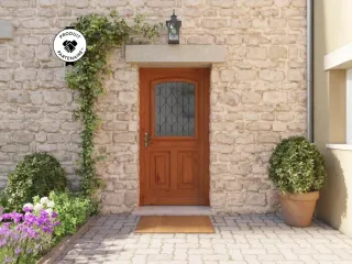 Entrée de maison en pierre avec une porte en bois, décorée de plantes grimpantes et d'arbustes en pot.