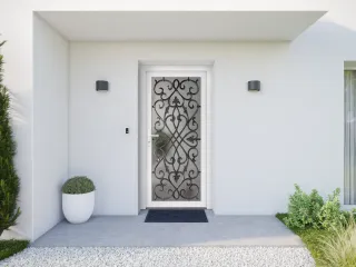 Entrée de maison moderne avec une porte blanche ornée de ferronnerie noire, encadrée par des murs blancs et des plantes vertes.