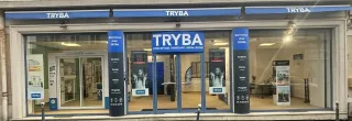 La devanture du magasin Tryba présente une vitrine moderne avec des portes vitrées et des panneaux signalétiques bleus, mettant en avant des promotions